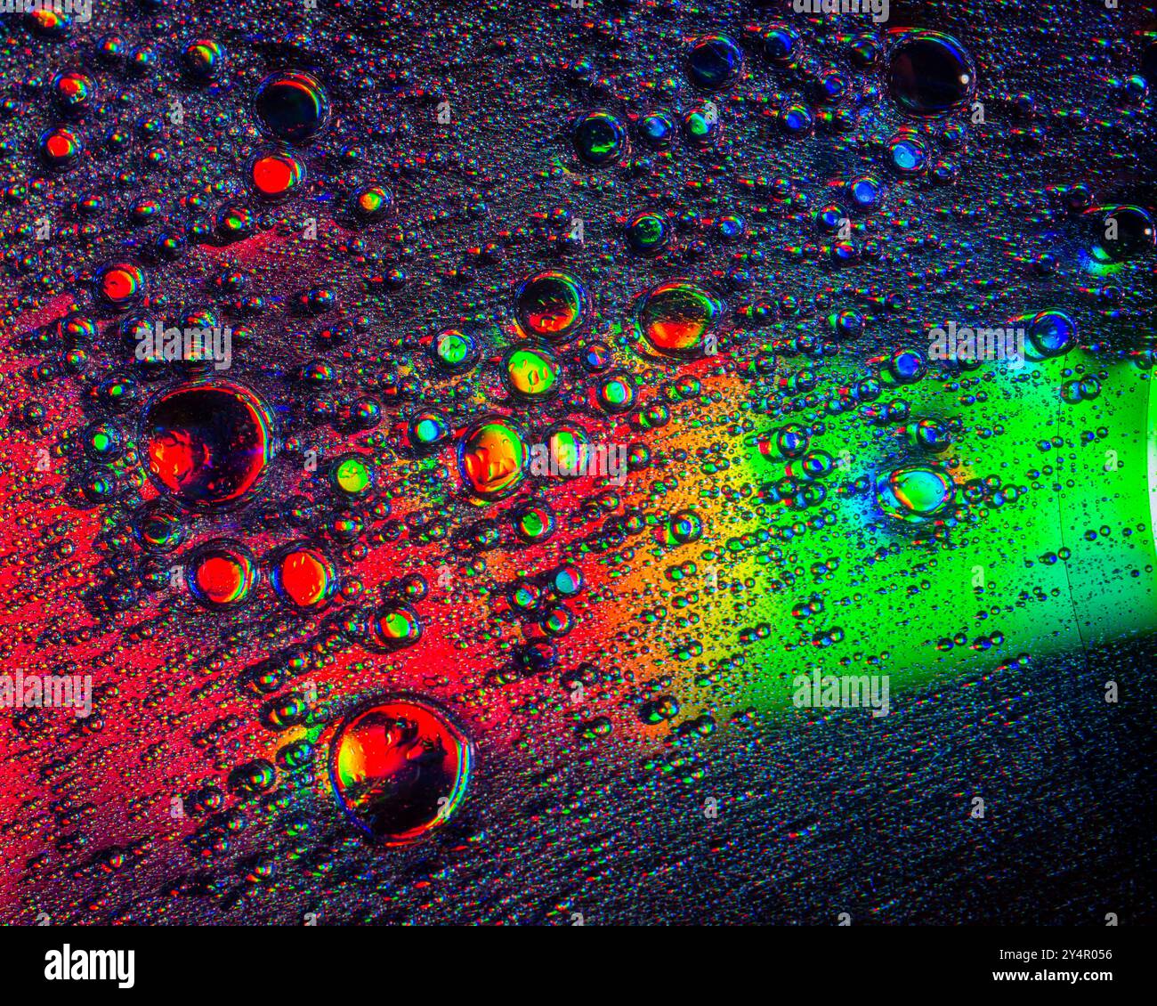 Une photo macro montrant des motifs et des couleurs de gouttes d'huile flottant sur l'eau Banque D'Images