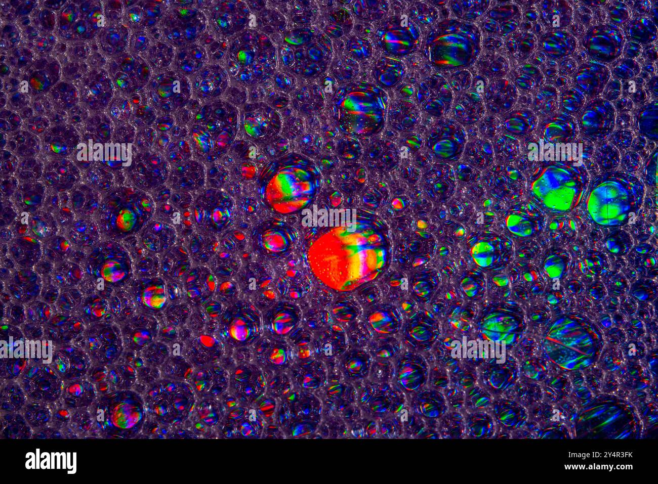 Une photo macro montrant des motifs et des couleurs de gouttes d'huile flottant sur l'eau Banque D'Images