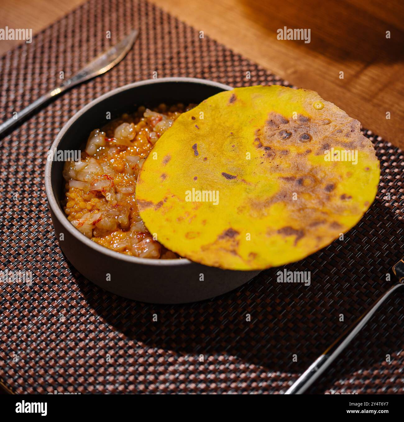 Présentation rustique d'un plat indien classique avec un roti frais et un chutney épicé sur une table en bois Banque D'Images