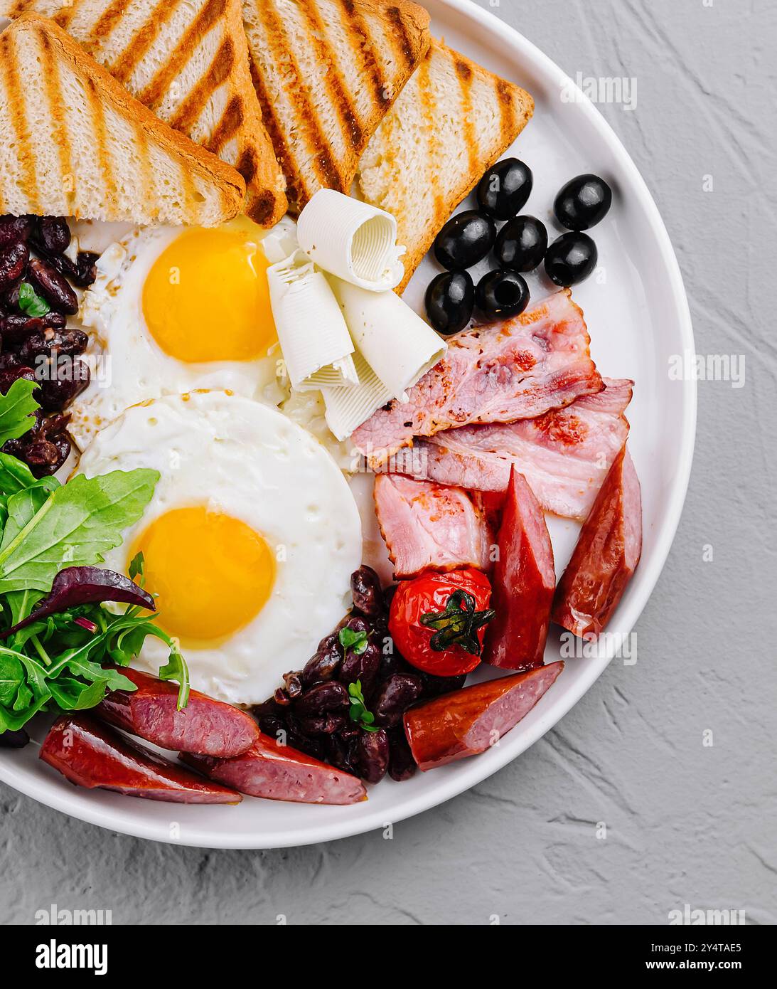 Vue aérienne d'une assiette copieux petit-déjeuner avec œufs, bacon, pain grillé et légumes frais Banque D'Images