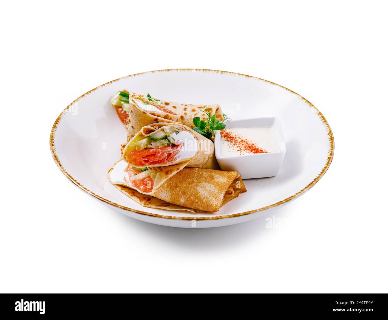 Crêpes au saumon et garniture au fromage à la crème servies sur assiette blanche avec sauce à la crème sure et décorées à l'aneth Banque D'Images