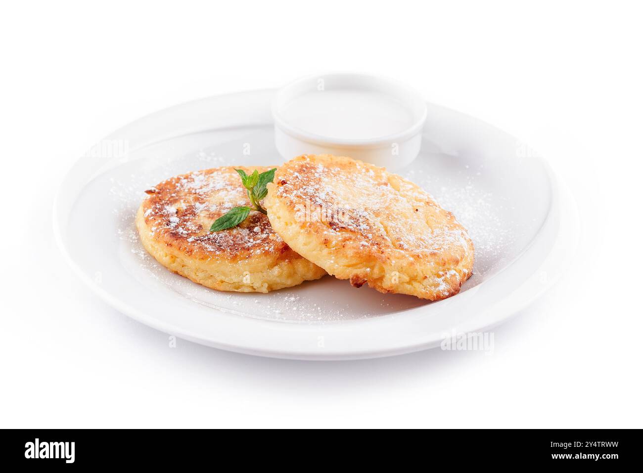 Deux délicieuses crêpes au fromage maison avec du sucre en poudre sont servies sur une assiette blanche avec de la crème sure et de la menthe Banque D'Images