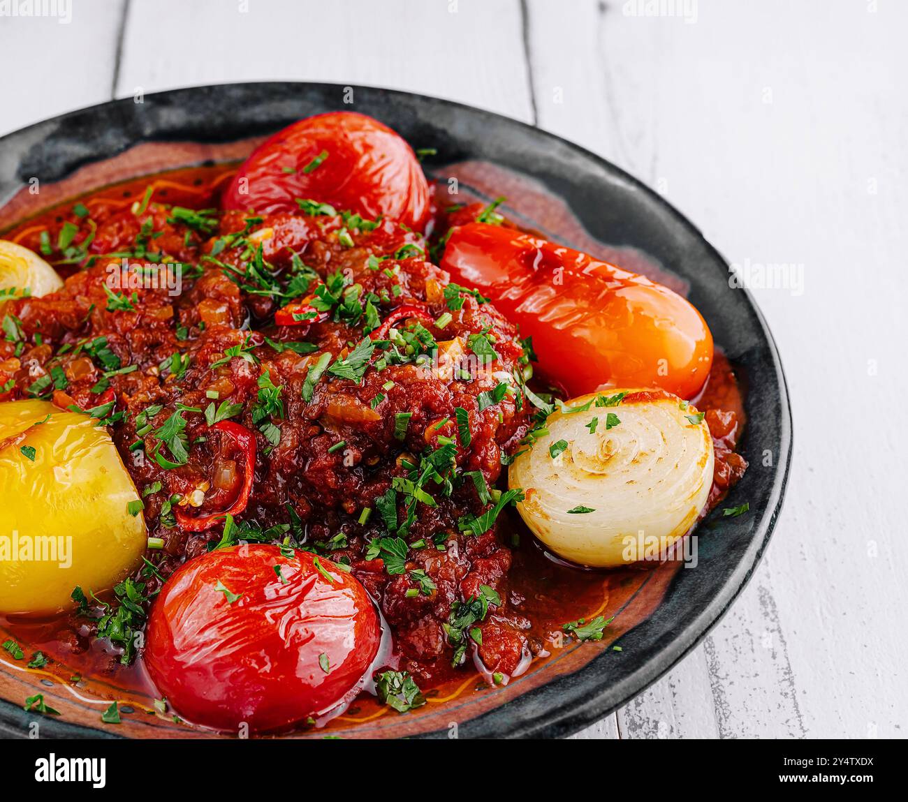 Ragoût de bœuf délicieux et copieux mijoté avec tomates, oignons et poivrons et garni d'herbes fraîches Banque D'Images