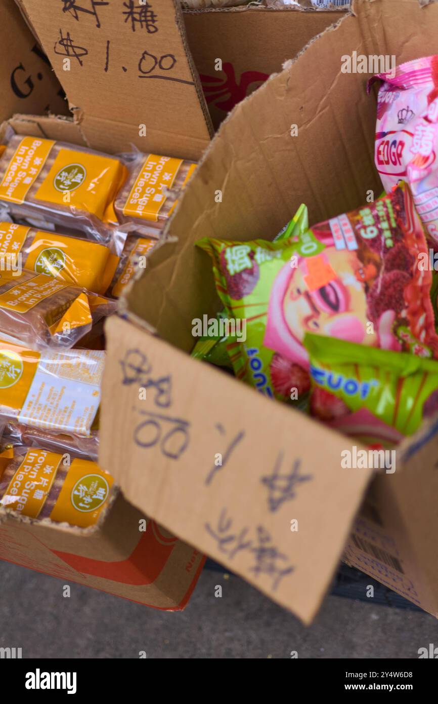 New York, États-Unis -19 septembre 2024 : boîte en carton remplie de divers bonbons chinois emballés individuellement sur un marché, étiquettes visibles et PRI Banque D'Images