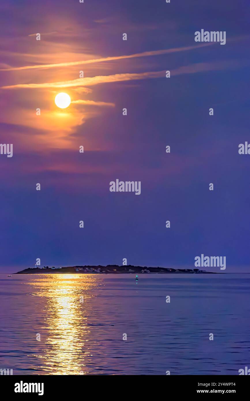 Récolte Super Moon Rising au-dessus de Bakers Island avec un ciel violet profond et des nuages colorés Banque D'Images