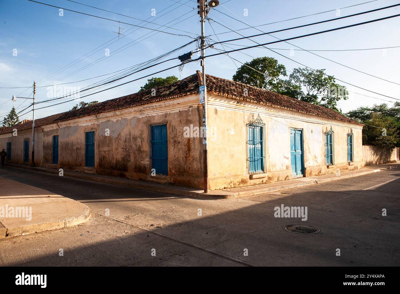 Ancienne maison de style colonial avec une façade jaune et des volets bleus. La maison a un toit en tuiles. L'atmosphère générale de l'image est une atmosphère de tranquillité Banque D'Images