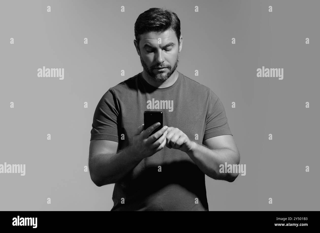 Portrait d'un homme joyeux utilisant un téléphone portable isolé sur un arrière-plan de studio. Homme caucasien utilisant le téléphone portable de smartphone pour les appels, les médias sociaux Banque D'Images