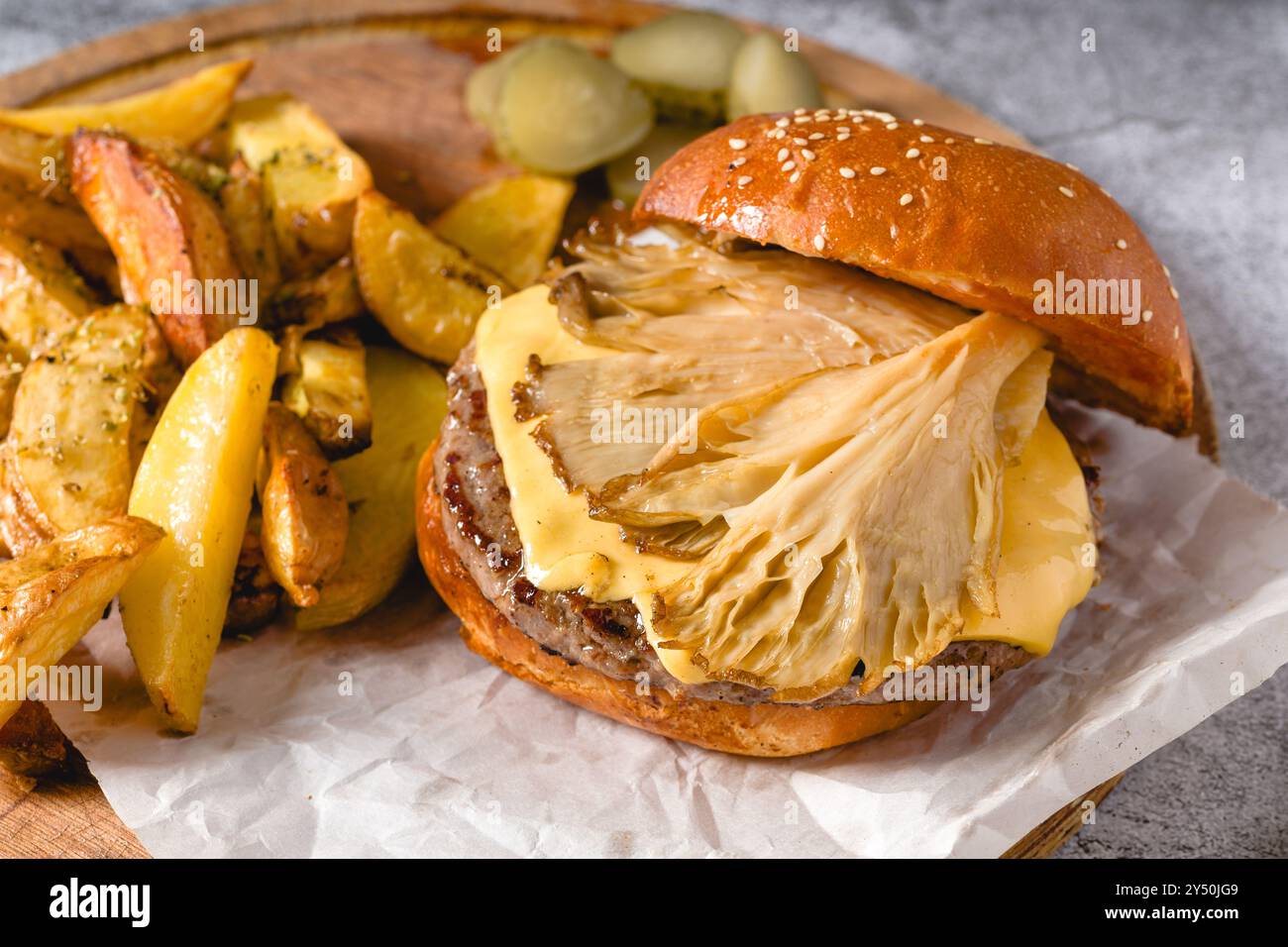 Hamburger avec des huîtres et du fromage cheddar sur une planche à découper en bois Banque D'Images