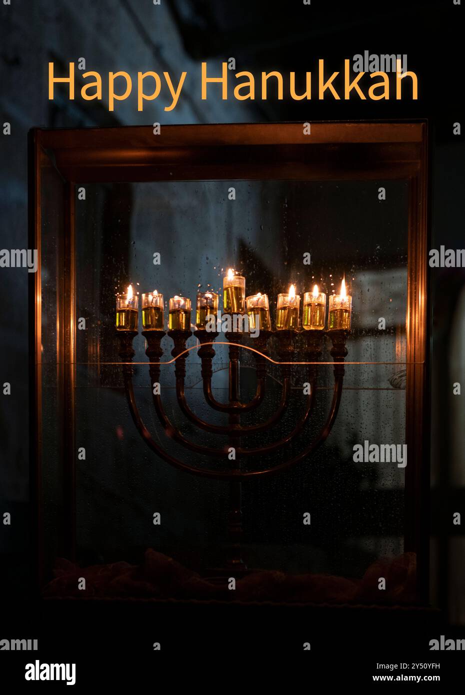 Hanukkah salutation en anglais avec une menorah devant une maison à Jérusalem, Israël, avec huit bougies à huile brûlant la huitième nuit du holi juif Banque D'Images