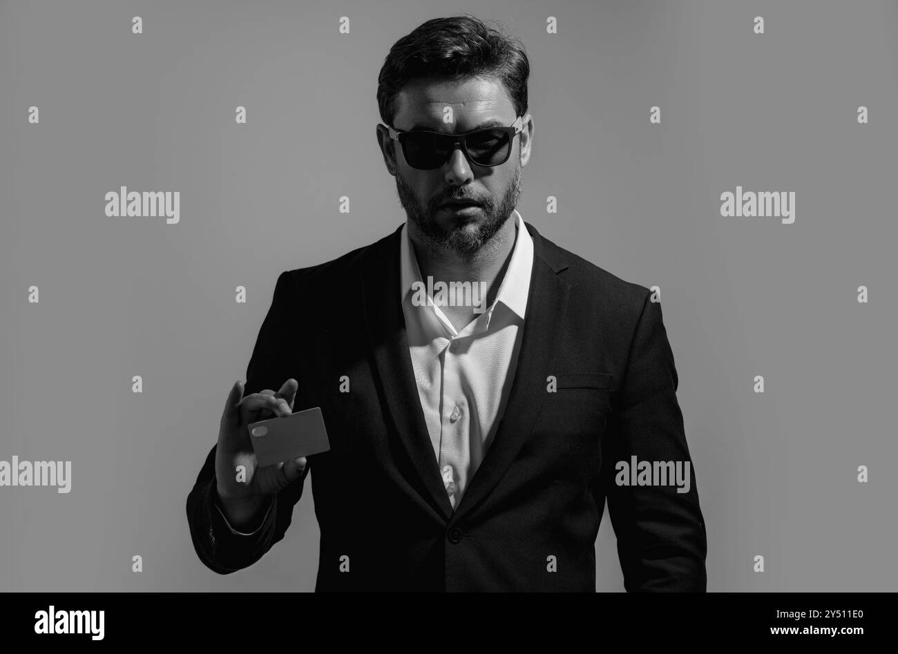 Homme d'affaires tenant une carte de crédit sur fond gris isolé. Homme hispanique montrant la carte de crédit. Carte bancaire de crédit ou de dépôt. Concept d'achat en ligne Banque D'Images