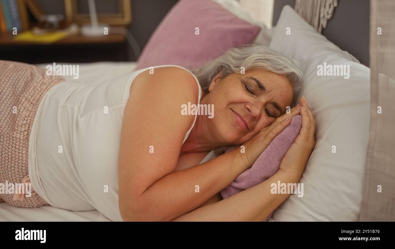 Femme mature dormant confortablement sur un lit dans une chambre confortable, mettant en valeur un moment serein et paisible à l'intérieur à la maison Banque D'Images