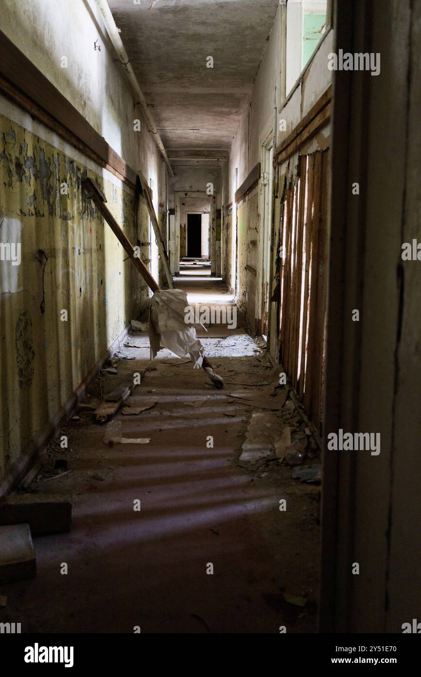 Un couloir long et sombre s'étend devant vous, avec un escalier situé au centre de l'espace faiblement éclairé Banque D'Images Un couloir long et sombre s'étend devant vous, avec un escalier situé au centre de l'espace faiblement éclairé Banque D'Images