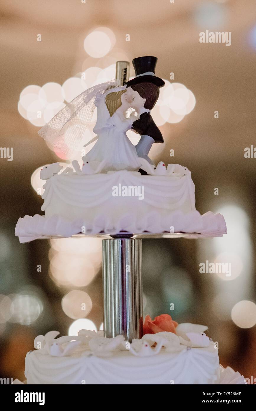 Gâteau de mariage topper avec mariée et marié, éclairé par des lumières bokeh douces. Banque D'Images