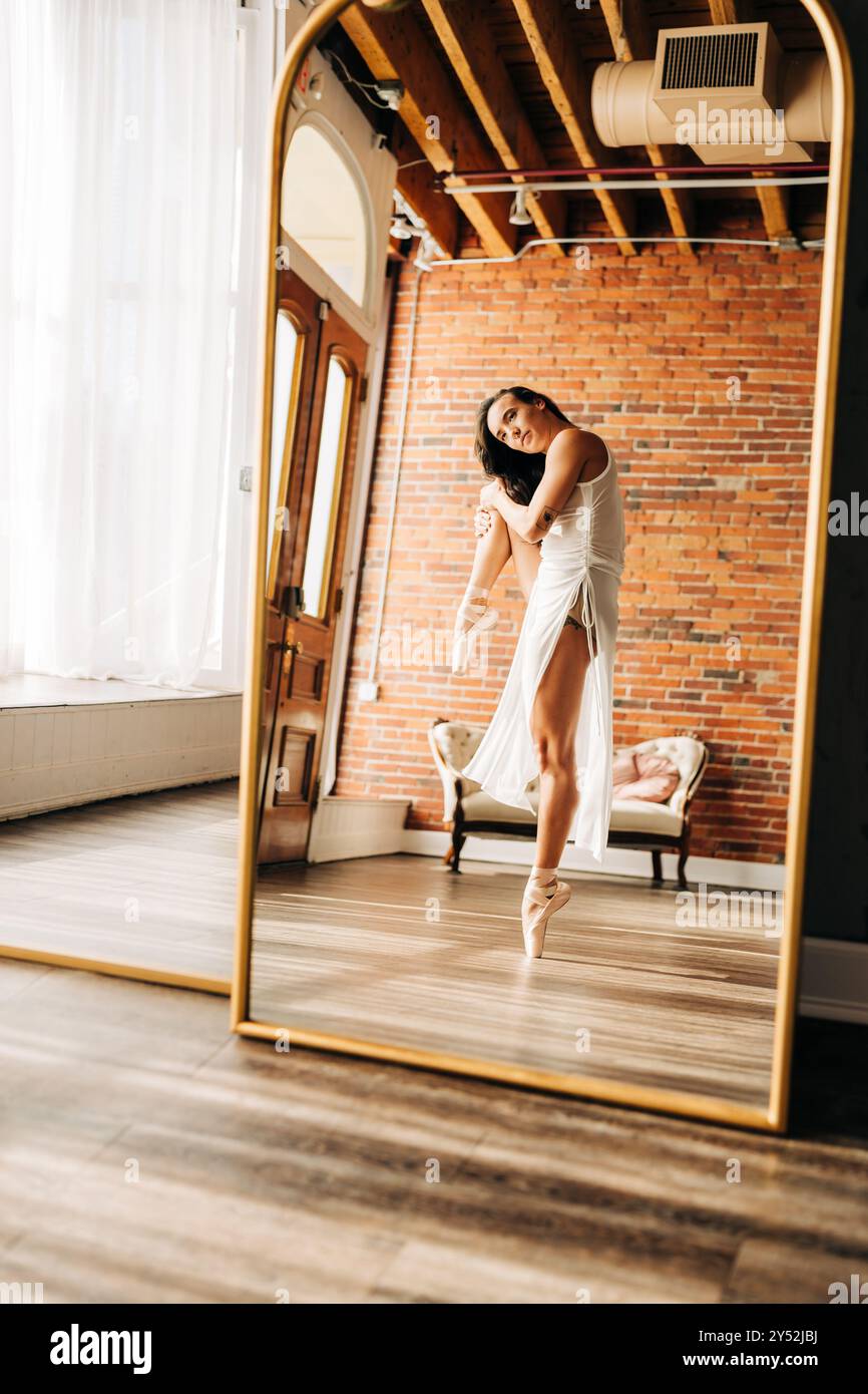 Danseuse de ballet en robe blanche, reflétée dans un miroir avec mur de briques Banque D'Images