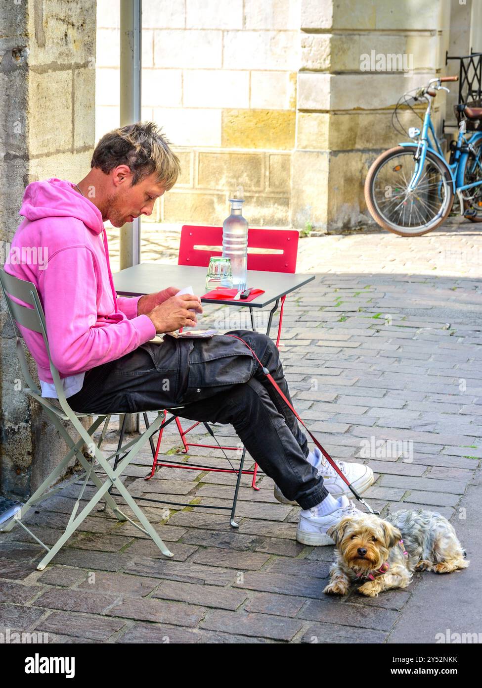 Jeune homme assis à la terrasse extérieure café avec chien Cairn terrier - Tours, Indre-et-Loire (37), France. Banque D'Images