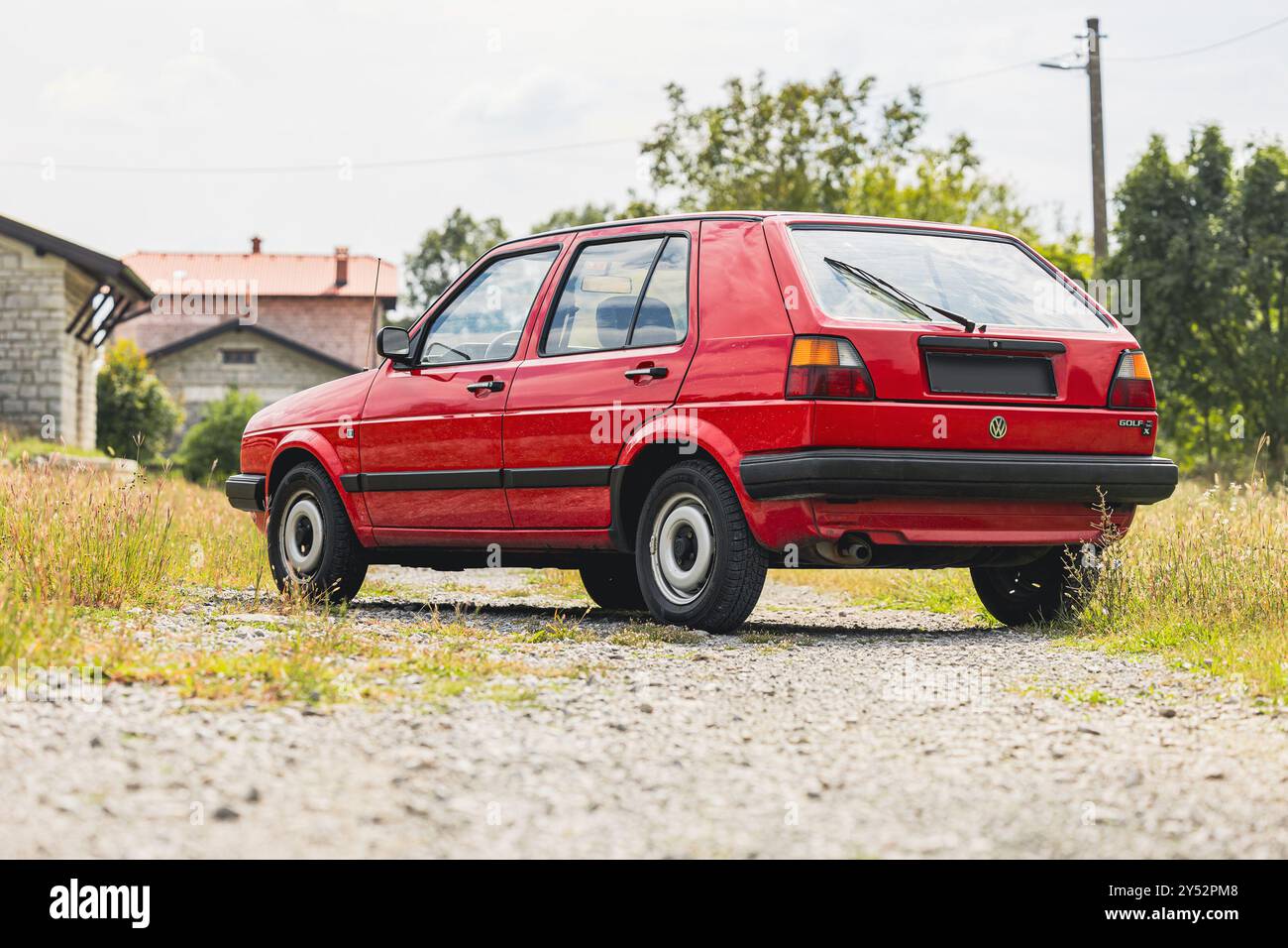 Stanjel, Slovénie, 9,2024 : Old Volkswagen golf de couleur rouge et 5 portes, 1,6D diesel pose sur une station devant un majestueux village de Stanjel Banque D'Images