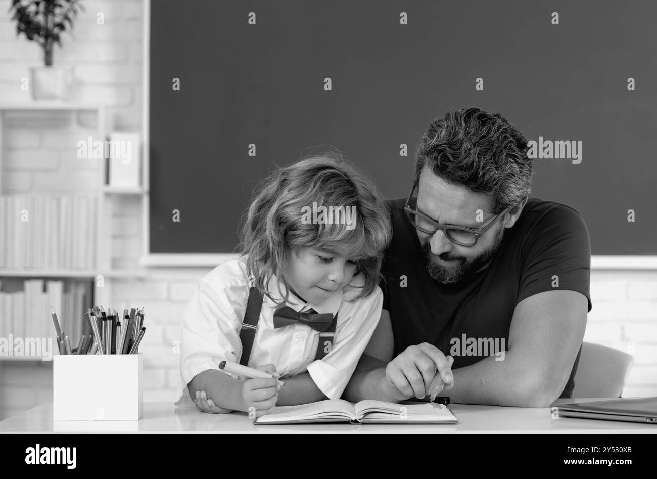Professeur de père aidant un garçon de fils dans les cours d'école. Banque D'Images