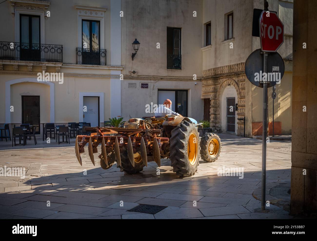 Un agriculteur italien conduit son tracteur d'époque avec une charrue attachée au centre de Presicce, province de Lecce, Pouilles, Italie. Banque D'Images Un agriculteur italien conduit son tracteur d'époque avec une charrue attachée au centre de Presicce, province de Lecce, Pouilles, Italie. Banque D'Images
