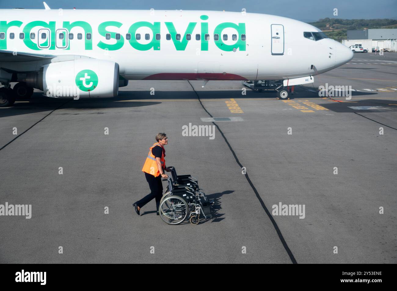 Perpignan, France. Aéroport avec Transavia avion et travailleur avec fauteuil roulant Banque D'Images