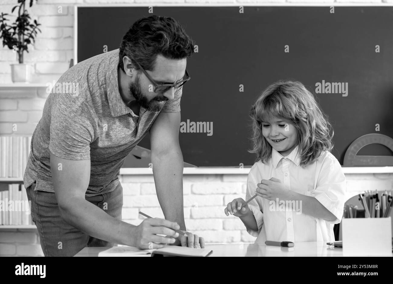 Professeur de père aidant un garçon de fils dans les cours d'école. Drôle de garçon d'école primaire heureux. Banque D'Images