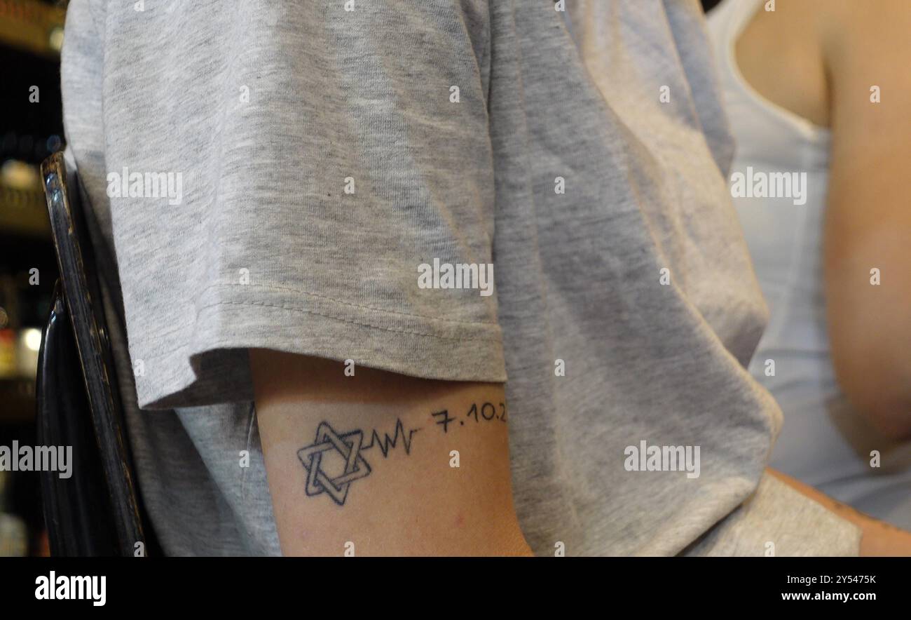 JÉRUSALEM - 19 SEPTEMBRE : une jeune femme israélienne avec Star of David et la date du 7 octobre 2023 tatouée sur son bras comme mémorial vivant du massacre du Hamas, qui a coûté la vie à près de 1 200 personnes dans le sud d'Israël l'année dernière, se trouve dans un bar du marché de Mahane ou Machane Yehuda souvent appelé "le Shuk", un marché en plein air, au milieu des batailles continues entre Israël et le groupe militant Hamas dans la bande de Gaza le 19 septembre 2024 à Jérusalem. Israël Banque D'Images