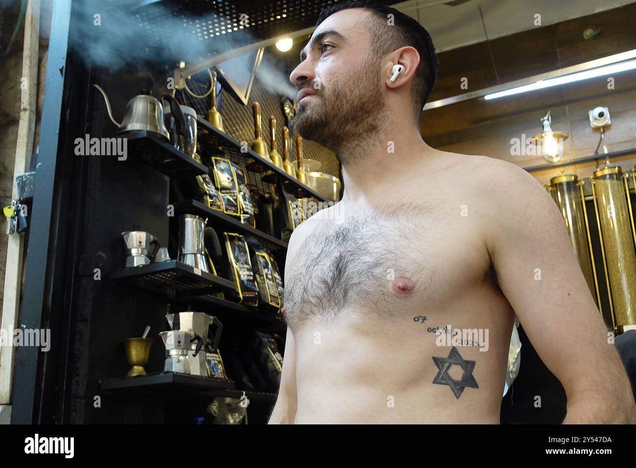 JÉRUSALEM - 19 SEPTEMBRE : un jeune israélien avec Star of David et la date du 7 octobre 2023 tatouée sur son corps comme mémorial vivant du massacre du Hamas, qui a coûté la vie à près de 1 200 personnes dans le sud d'Israël l'année dernière, se trouve dans un magasin du marché de Mahane ou Machane Yehuda souvent appelé "le Shuk", un marché en plein air, au milieu des batailles continues entre Israël et le groupe militant Hamas dans la bande de Gaza le 19 septembre 2024 à Jérusalem. Israël Banque D'Images