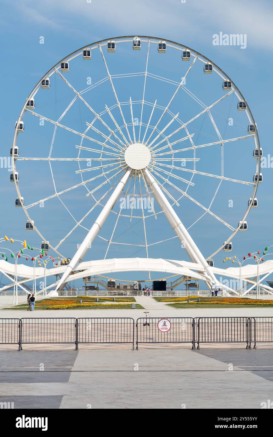 Bakou, Azerbaïdjan - 4 mai 2024 : vue de la grande roue Baku Eye, située à côté du centre commercial Deniz. La roue est en arrière-plan avec peu de gens marchant au premier plan Banque D'Images