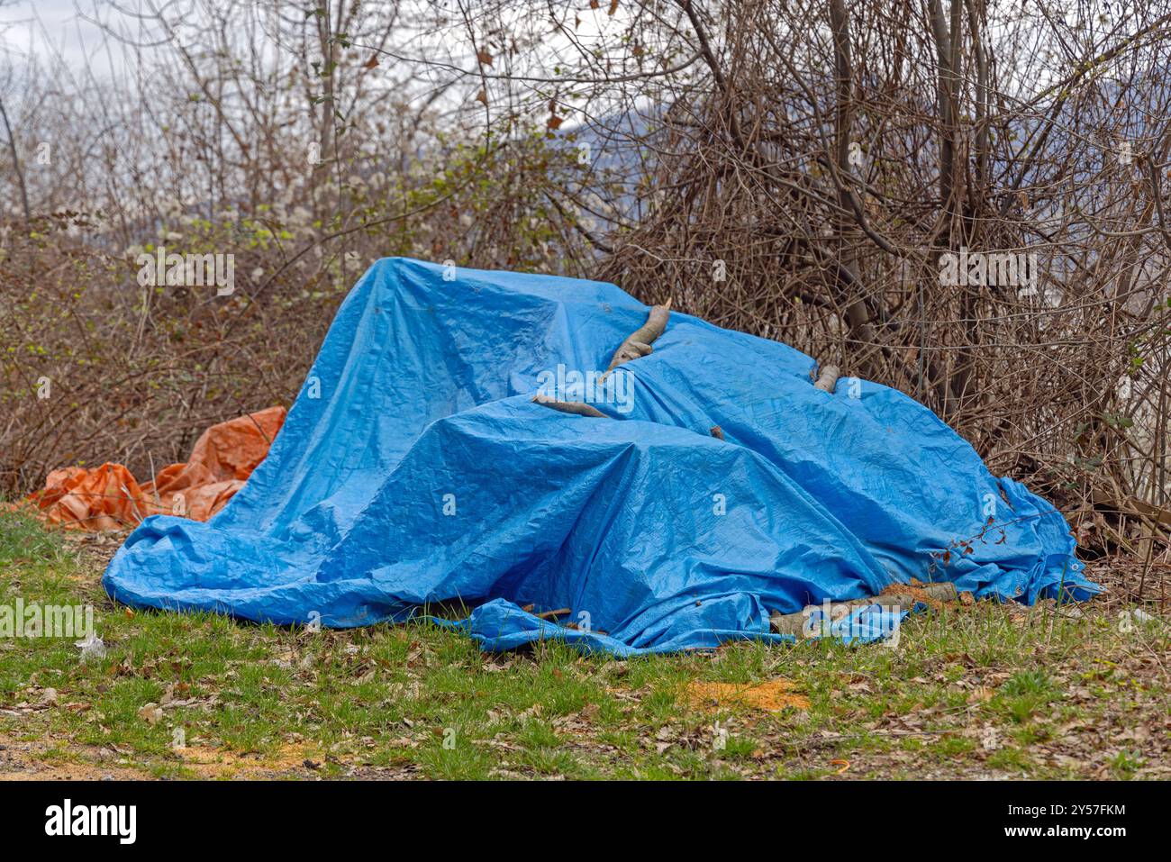 Grosse pile de trucs cachés sous la couverture de bâche bleue dans Yard Garden Banque D'Images