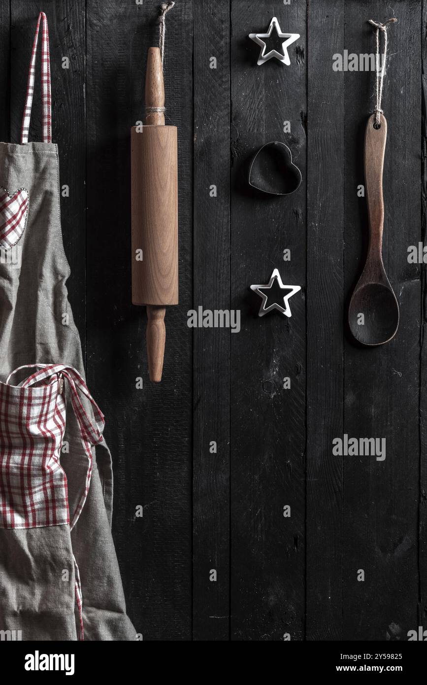 Tablier de cuisine, rouleau à pâtisserie et d'autres outils de cuisine pendus à des clous sur un mur en bois Banque D'Images