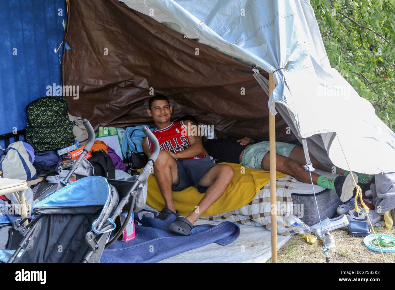 Plus d'un an s'est écoulé depuis que le gouverneur du Texas Greg Abbott a orchestré le premier transport de demandeurs d'asile à Chicago. Plus de 47 000 demandeurs d'asile sont arrivés par bus, souvent sans argent ni effets personnels. La grande majorité sont originaires du Venezuela et d'Amérique centrale. Les demandeurs d’asile s’abritent temporairement dans un espace vert adjacent à un poste de police dans le Near West Side de Chicago aux États-Unis. Banque D'Images