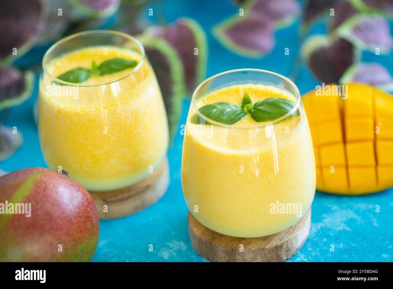 Lassi à la mangue fraîche dans des verres sur fond bleu avec espace de copie. Boisson froide ayurvédique indienne saine detoxic avec mangue. Lassi fraîcheur en yogur Banque D'Images