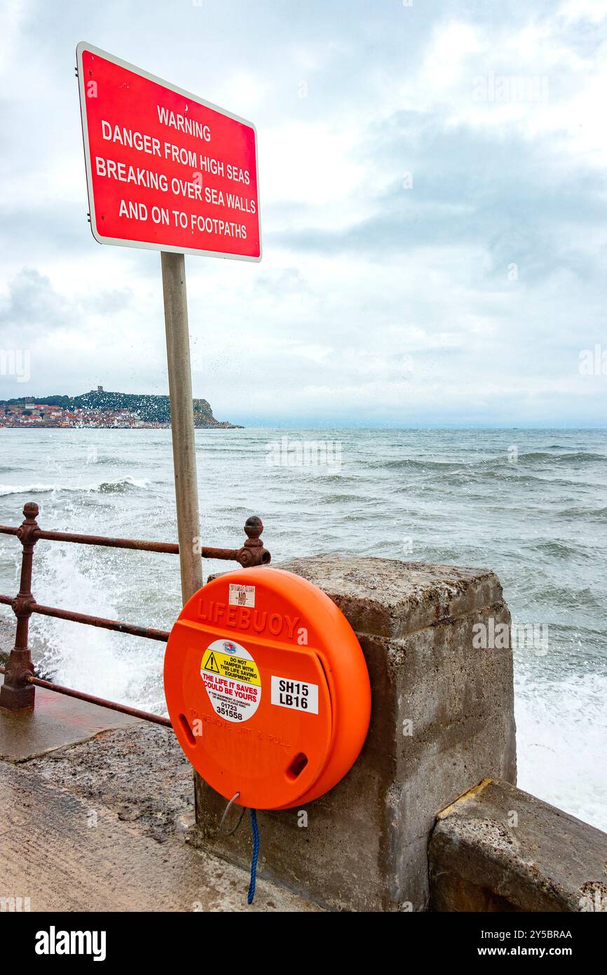 scarborough yorkshire Seaside promenade avec un panneau d'avertissement de danger sur la haute mer et une bouée de sauvetage le long des balustrades métalliques surplombant l'océan Banque D'Images