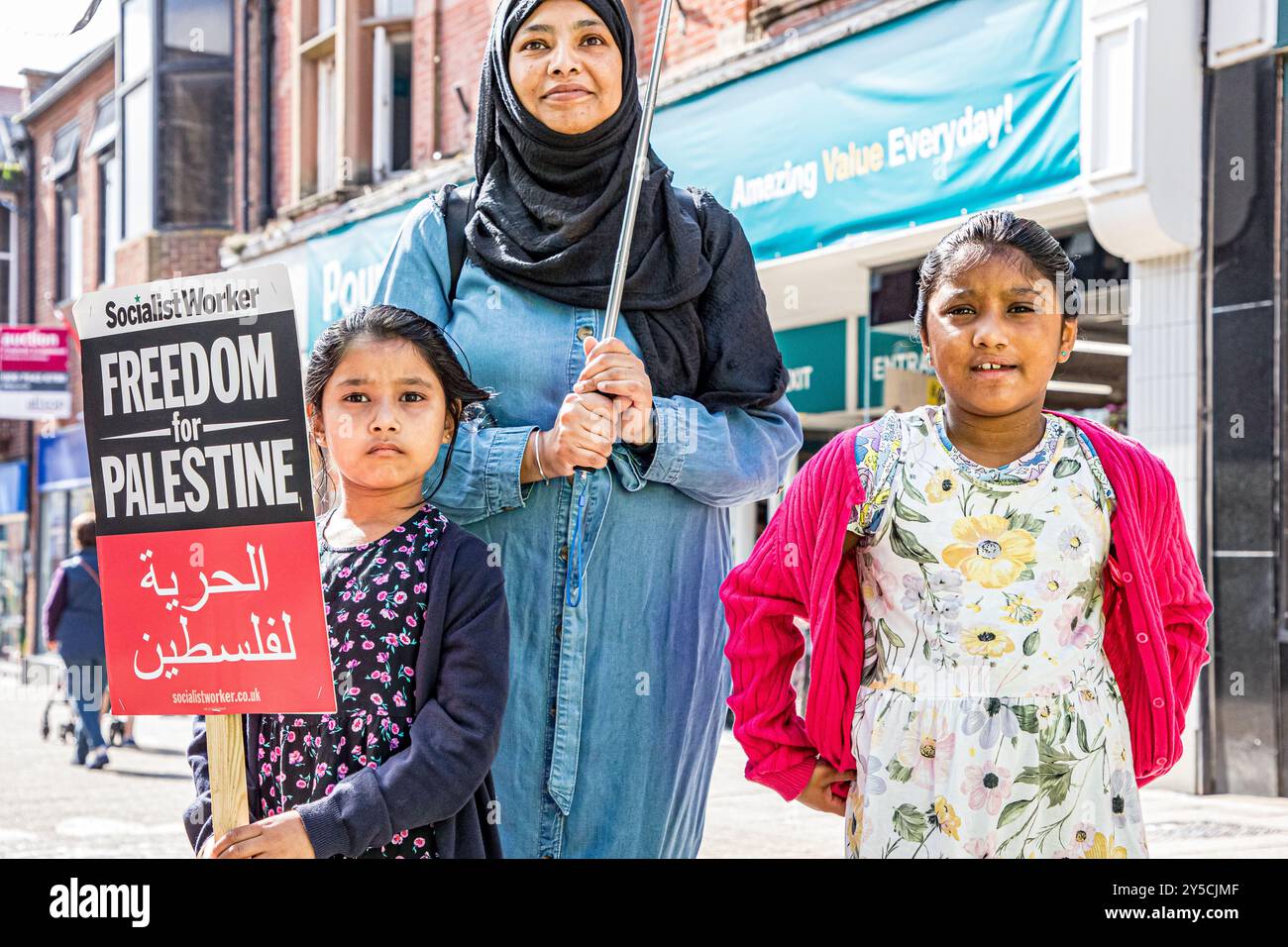 Dorchester, Royaume-Uni, le 21 septembre 2024, mère et deux enfants portant des banderoles alors que les militants pro-palestiniens ont organisé une marche 'End the Genocide - Stop arming Israel' dans le centre-ville de Dorchester. La campagne de solidarité Dorset Palestine s'est réunie devant le cinéma de l'Odéon et a défilé le long de South Street pour protester devant Barclays Bank, qui, selon le groupe, finance la guerre d'Israël avec le Hamas à Gaza. Crédit John Rose/Alamy Live News Banque D'Images