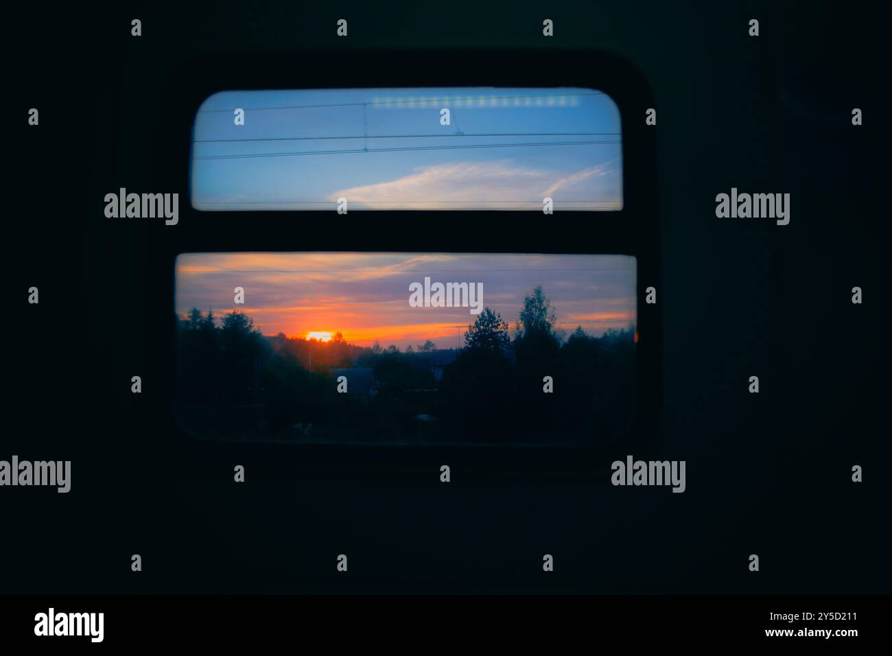 La vue depuis la fenêtre du train est d'un beau coucher de soleil sur une forêt sombre, créant une atmosphère paisible et sereine. C'est une soirée sur un voyage, a Banque D'Images