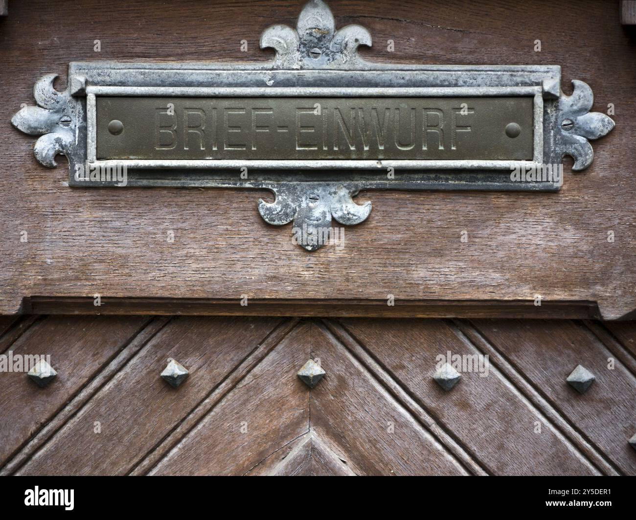 Fente de lettre en métal ornée sur une porte en bois Banque D'Images