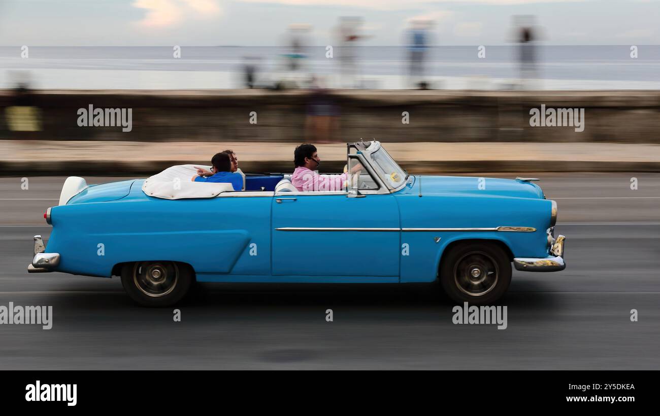 737 vieille voiture classique américaine bleue -Ford de 1952- conduite sur la digue de Malecon Promenade avec les habitants locaux sur le parapet du front de mer. La Havane-Cuba. Banque D'Images