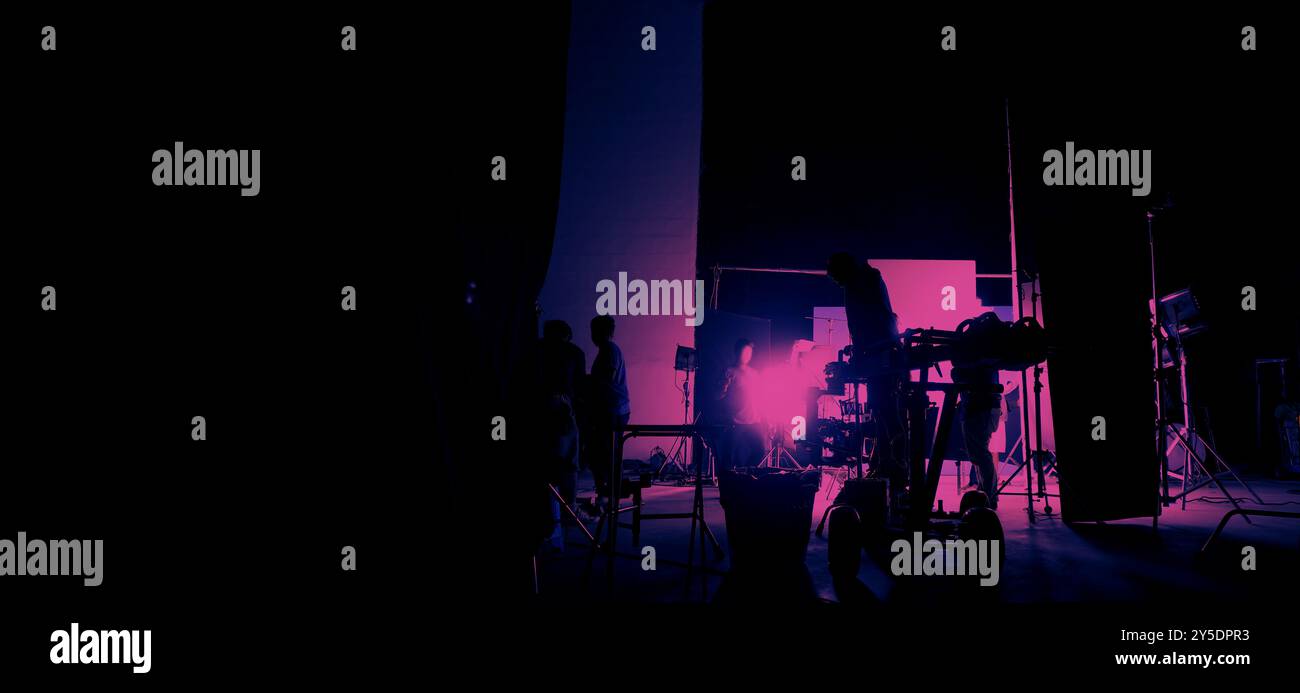 Silhouette des équipes de film et de la caméra vidéo sur une grue de chariot spéciale avec l'équipement de lumières de film et l'ensemble d'écran bleu. Production de films dans les coulisses stu Banque D'Images