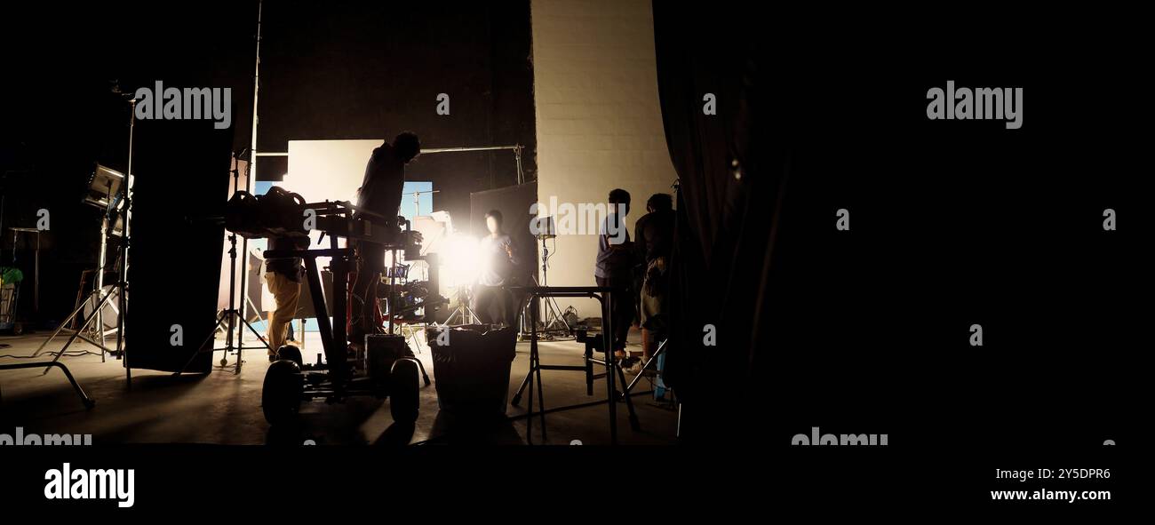 Silhouette des équipes de film et de la caméra vidéo sur une grue de chariot spéciale avec l'équipement de lumières de film et l'ensemble d'écran bleu. Production de films dans les coulisses stu Banque D'Images