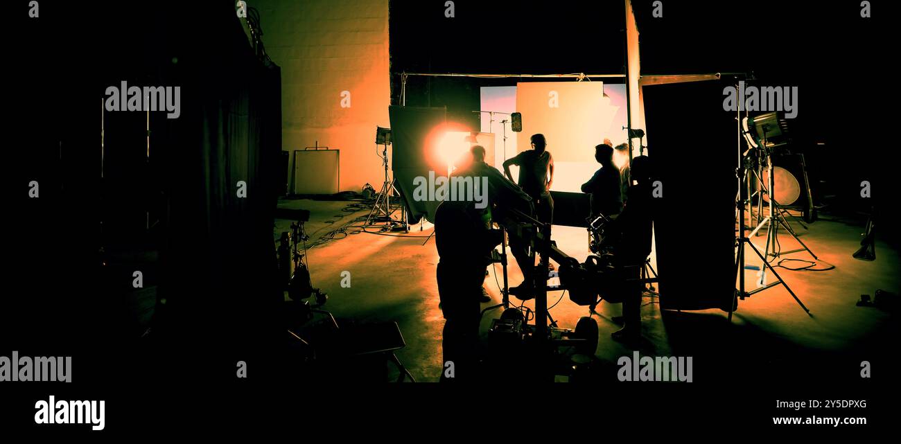 Silhouette des équipes de film et de la caméra vidéo sur une grue de chariot spéciale avec l'équipement de lumières de film et l'ensemble d'écran bleu. Production de films dans les coulisses stu Banque D'Images