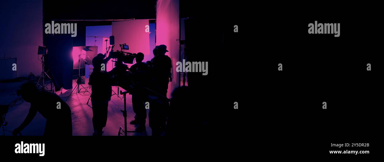 Silhouette des équipes de film et de la caméra vidéo sur une grue de chariot spéciale avec l'équipement de lumières de film et l'ensemble d'écran bleu. Production de films dans les coulisses stu Banque D'Images