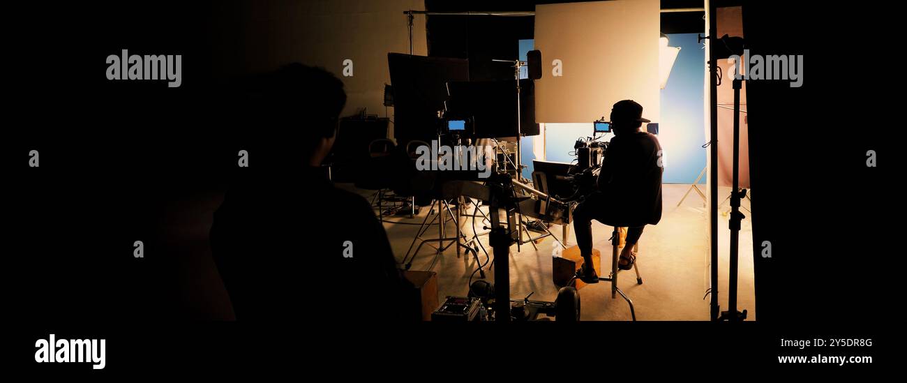 Silhouette des équipes de film et de la caméra vidéo sur une grue de chariot spéciale avec l'équipement de lumières de film et l'ensemble d'écran bleu. Production de films dans les coulisses stu Banque D'Images