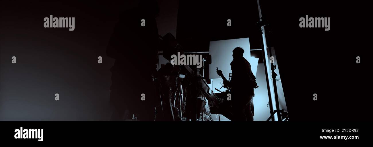 Silhouette des équipes de film et de la caméra vidéo sur une grue de chariot spéciale avec l'équipement de lumières de film et l'ensemble d'écran bleu. Production de films dans les coulisses stu Banque D'Images