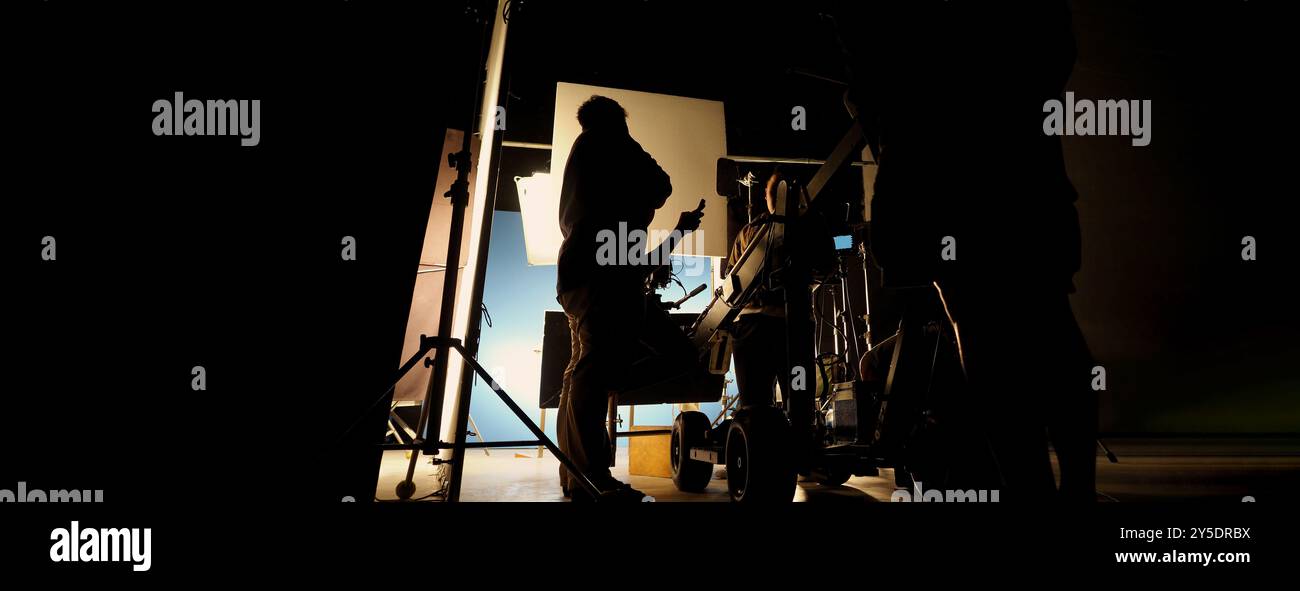 Silhouette des équipes de film et de la caméra vidéo sur une grue de chariot spéciale avec l'équipement de lumières de film et l'ensemble d'écran bleu. Production de films dans les coulisses stu Banque D'Images