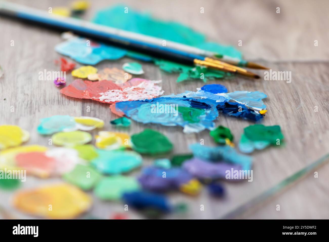 Une palette colorée de divers tubes de peinture et pinceaux disposés soigneusement sur une table en bois rustique, mettant en valeur les teintes vibrantes pour la créativité Banque D'Images