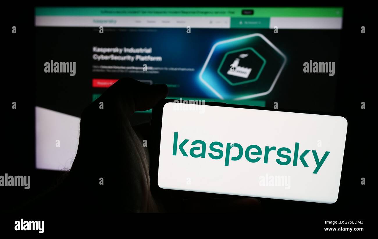 Dans cette illustration photo, une personne tient un téléphone portable avec le logo de la société russe de cybersécurité AO Kaspersky Lab en face de la page Web de l'entreprise. Banque D'Images