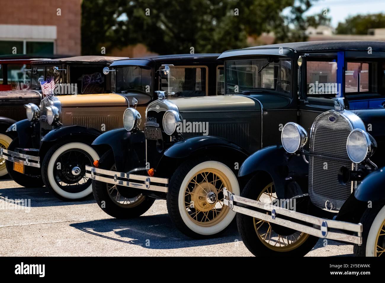 Une rangée de voitures Ford modèle A vintage est alignée dans un parking pour un salon de voitures anciennes. Les voitures présentent différentes couleurs et designs. Banque D'Images