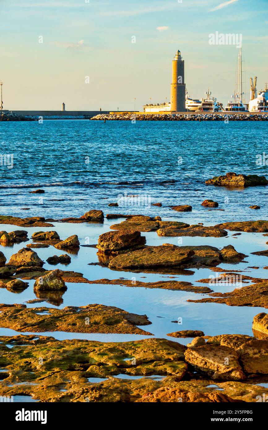 Le phare de Fanale dei Pisani vu de la côte rocheuse près de Terrazza Mascagni à Livourne, Italie, avec des marées reflétant le ciel. Banque D'Images