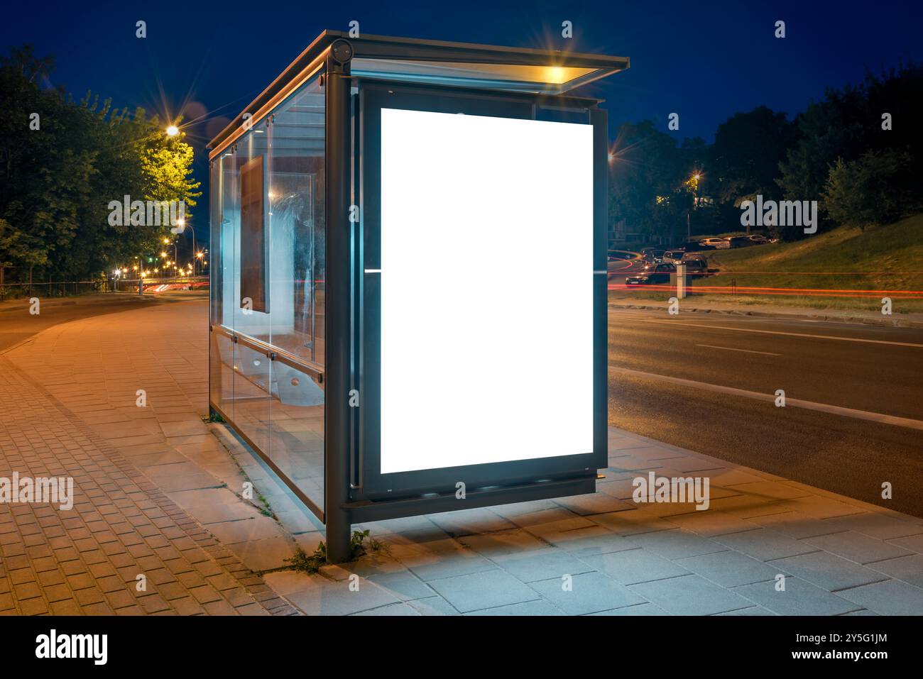 Maquette d'un panneau publicitaire d'arrêt de bus sur Une rue de la ville la nuit. Visionneuse d'affiche extérieure avec des pistes de lumière de voiture en arrière-plan Banque D'Images