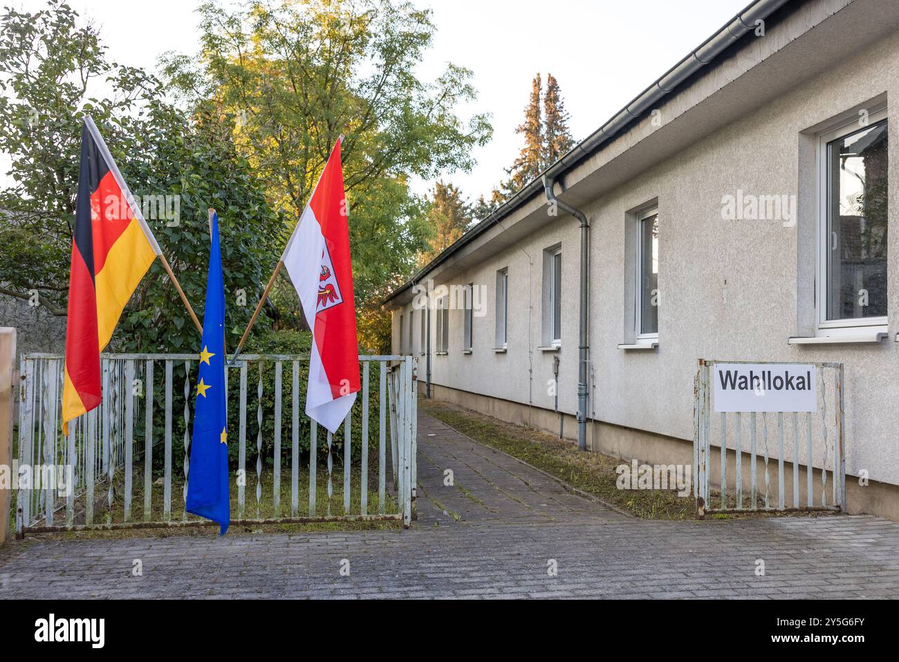 22 septembre 2024, Brandebourg, Golßen : un panneau et les drapeaux européens, allemands et du Brandebourg sont visibles à l'entrée d'un bureau de vote. Les élections d'État dans le Brandebourg ont lieu dimanche. Photo : Frank Hammerschmidt/dpa Banque D'Images