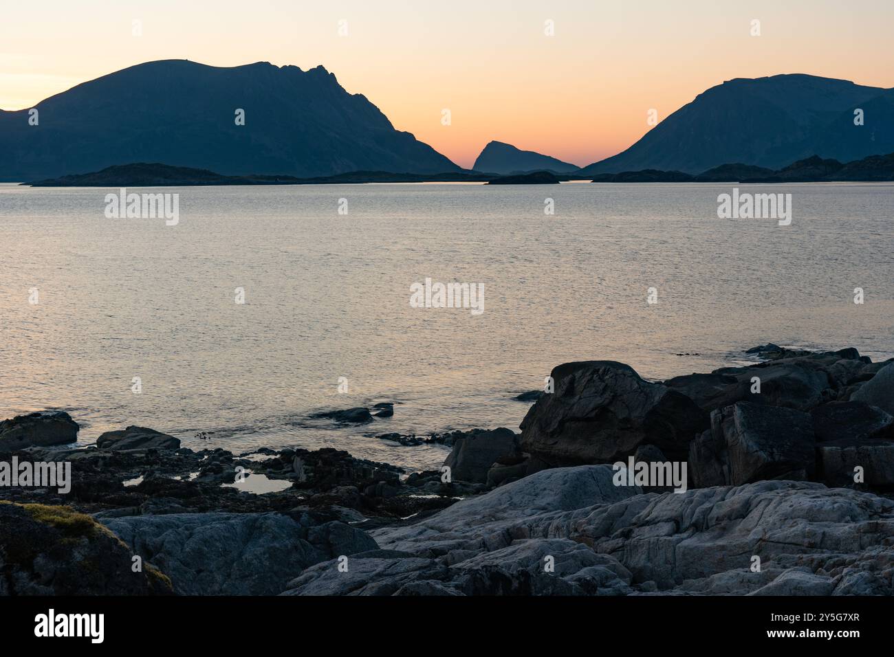 Coucher de soleil chaud nuit nord sur la plage de mer rocheuse avec des montagnes, Lofoten Norvège Banque D'Images